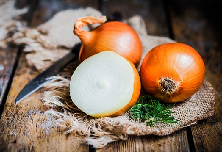 Golden onions on rustic wooden background